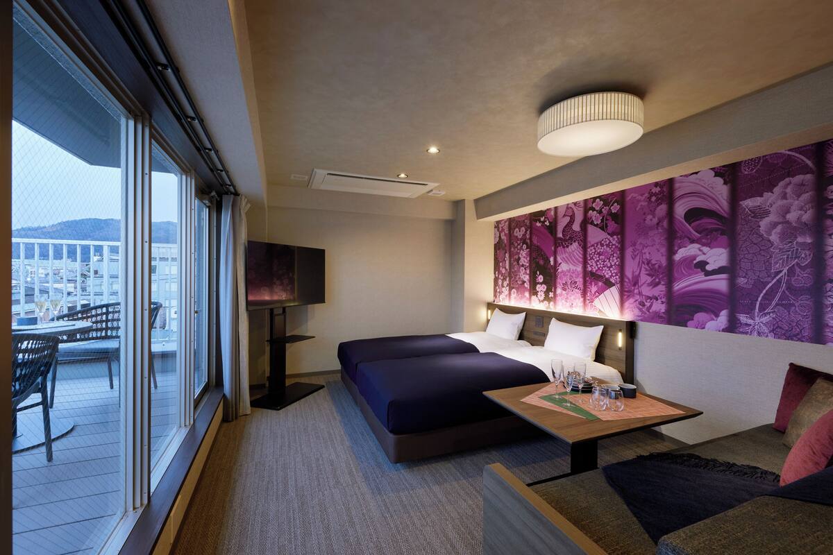 Een hotelkamer met een groot bed, een bureau en uitzicht op een balkon.