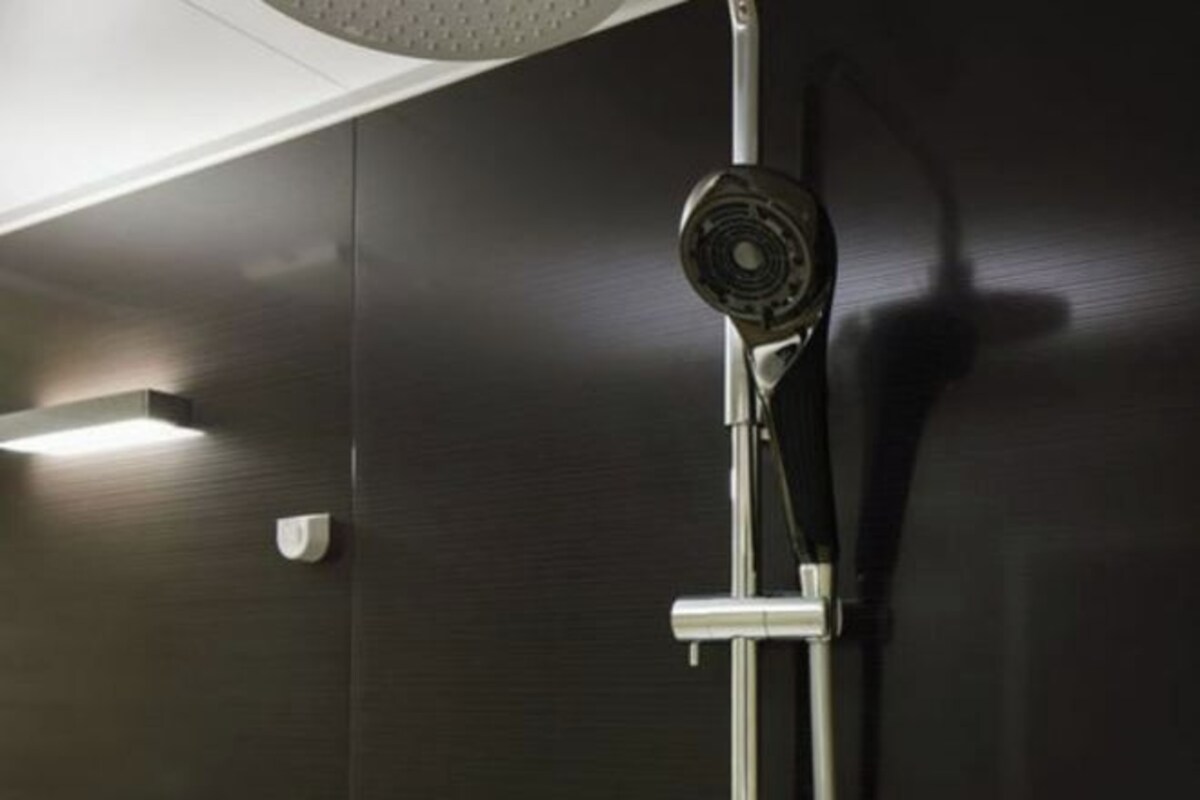 Ducha moderna con cabezal de ducha de mano y panel de control en la pared.