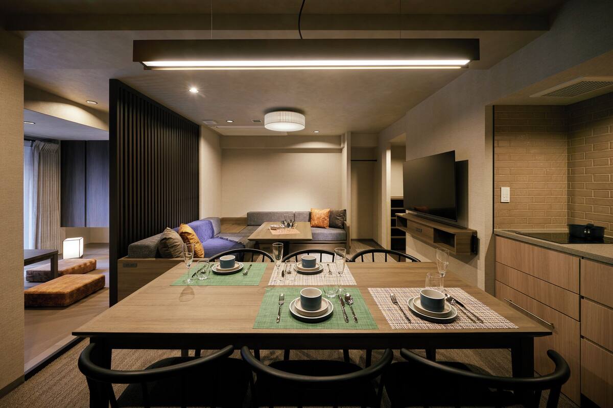 Een moderne hotelkamer met een zithoek, een bank, een televisie en een kitchenette.