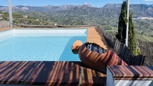 Piscina com vista para montanhas, um deck de madeira e uma estrutura de pérgula.