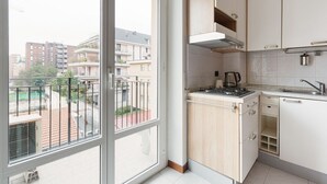 Et moderne køkken med gaskomfur, vask og skabe, samt en balkon med udsigt over byen.