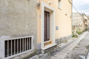 A building with a beige exterior, a brown door, a small window, and a number plate.