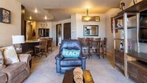 A living room with a leather chair labeled "BEACH," a sofa, a coffee table, and a bookshelf.