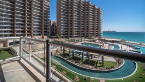 A high-rise hotel with multiple balconies, a pool area with lounge chairs, and a view of the ocean.