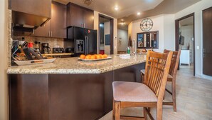A modern kitchen with dark wood cabinets, a granite countertop, and a large island with a chair.
