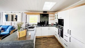 Eine moderne Küche mit weißen Schränken, einem schwarzen Kühlschrank und Holzboden.