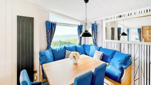 Ein Zimmer mit Holztisch, blau gepolsterten Sitzgelegenheiten und Blick auf das Meer.