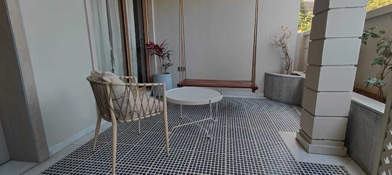 A small patio area with a wicker chair, a round table, and a swing.
