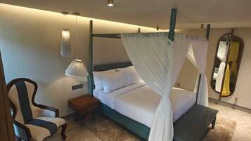 A bedroom with a four-poster bed, a chair, a bedside table, and a mirror.