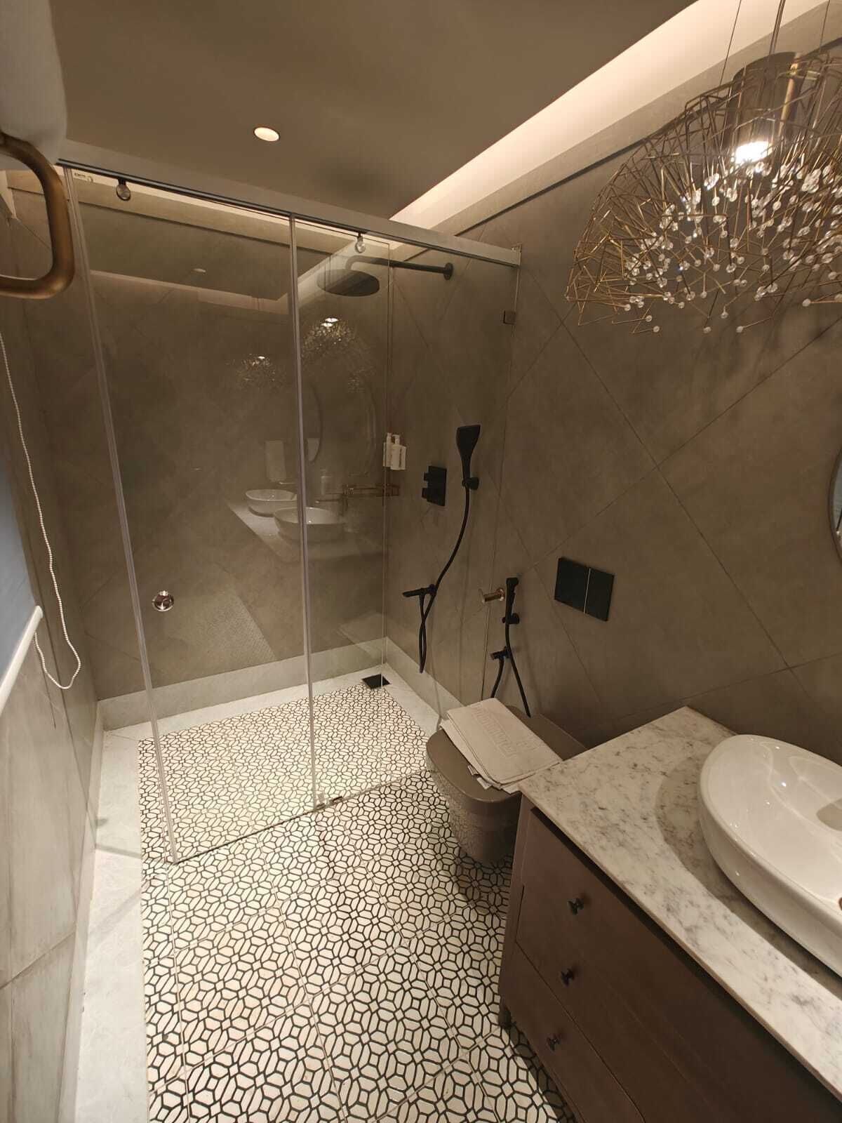 A modern bathroom with a glass-enclosed shower, a marble sink, and a patterned floor.