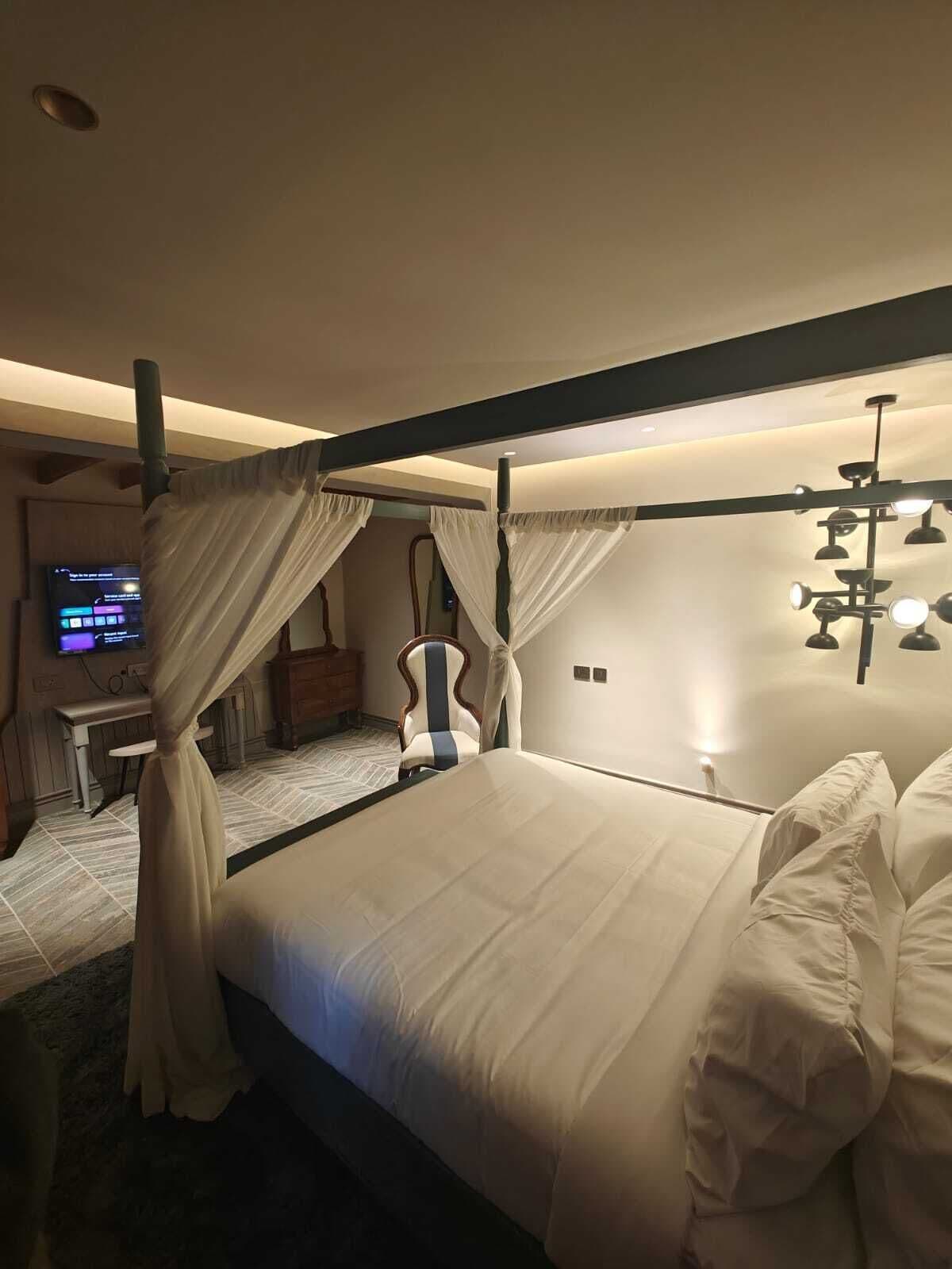 Un dormitorio con cama con dosel, un escritorio y una televisión.