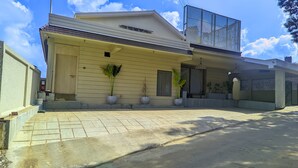 A modern two-story house with a flat roof, large windows, and a covered porch area. - Maison de Zen (Ooty)