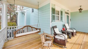 Un porche con una mecedora, sillas de mimbre y una mesa.