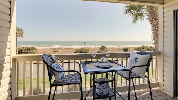 A balcony with a table and chairs overlooking a beach. - Scenic Oceanfront Condo in Myrtle Beach! (Myrtle Beach)