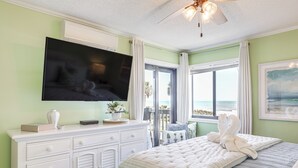 A bedroom with a large bed, a flat-screen TV mounted on the wall, a dresser, and a window with a view of the ocean. - Scenic Oceanfront Condo in Myrtle Beach! (Myrtle Beach)