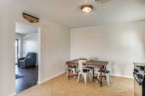 A dining area with a wooden table, white chairs, and a kitchen stove.