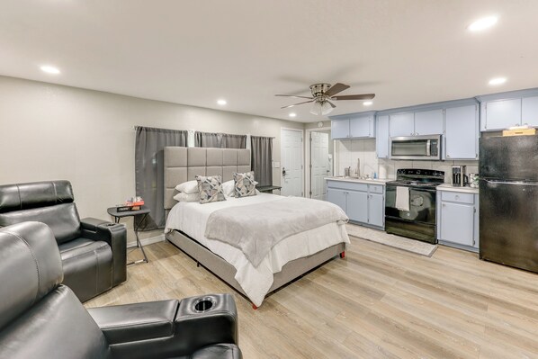 A modern bedroom with a large bed, a sofa, a small table, and a kitchenette with a microwave, stove, and refrigerator. - Private Yard: Pet-Friendly Studio in New Boston! (New Boston)