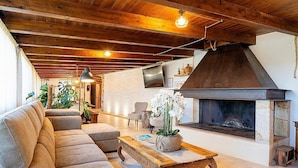 Ein gemütliches Wohnzimmer mit einer Couch, einem Holztisch, einem Kamin und einem an der Wand befestigten Fernseher.