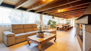 Ein geräumiges Wohnzimmer mit Holzboden, einem beigefarbenen Sofa, einem Couchtisch aus Holz und einem Kamin.