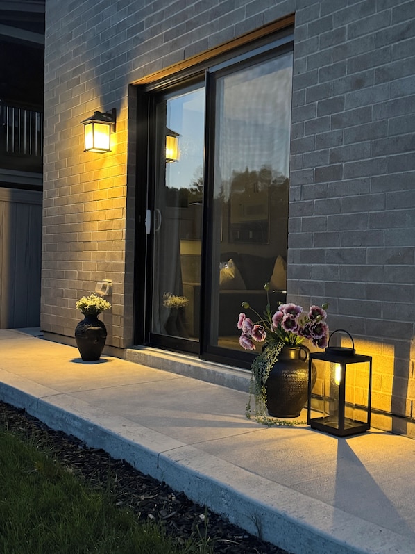 A modern building with a glass door and a concrete pathway. There are two potted plants on the pathway.