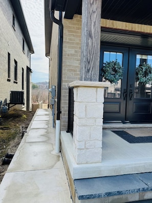 A modern building with a stone column, a brick facade, and a black door with wreaths.