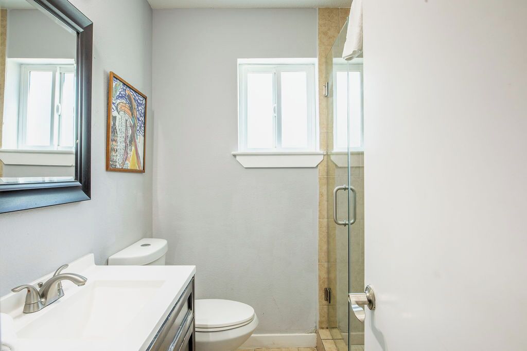 Une salle de bain avec un lavabo blanc, des toilettes et une cabine de douche en verre.