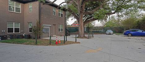 A parking lot with a building, a tree, and a blue car.