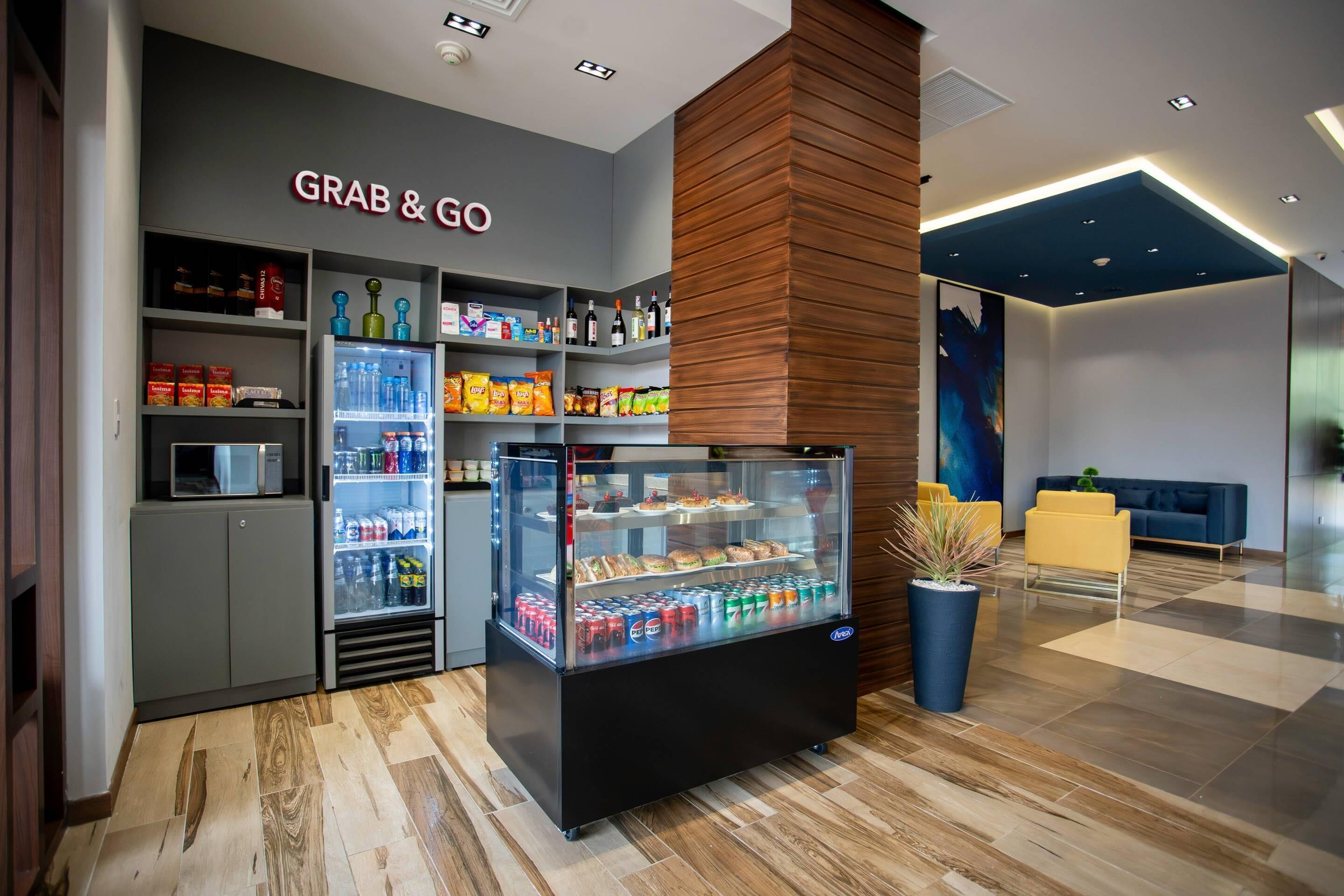 A 'Grab & Go' kiosk with refrigerated drinks and snacks, a microwave, and shelves stocked with various food items.