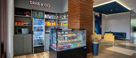 A 'Grab & Go' kiosk with refrigerated drinks and snacks, a microwave, and shelves stocked with various food items.