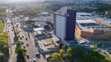 Un hotel amb una torre destacada, un aparcament i un carrer animat ple de cotxes.