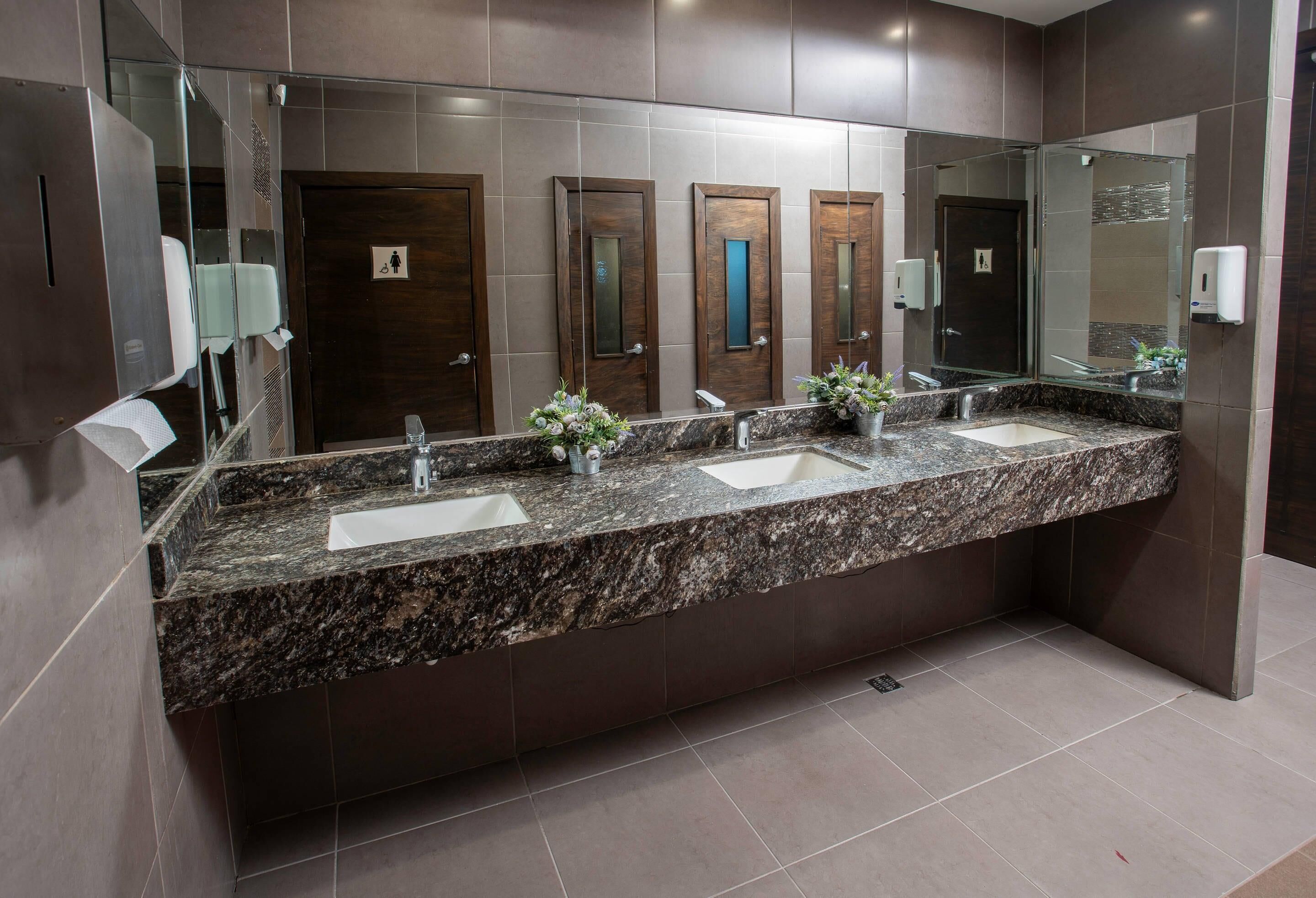 Une salle de bain moderne avec un comptoir en granit, deux lavabos et un grand miroir.