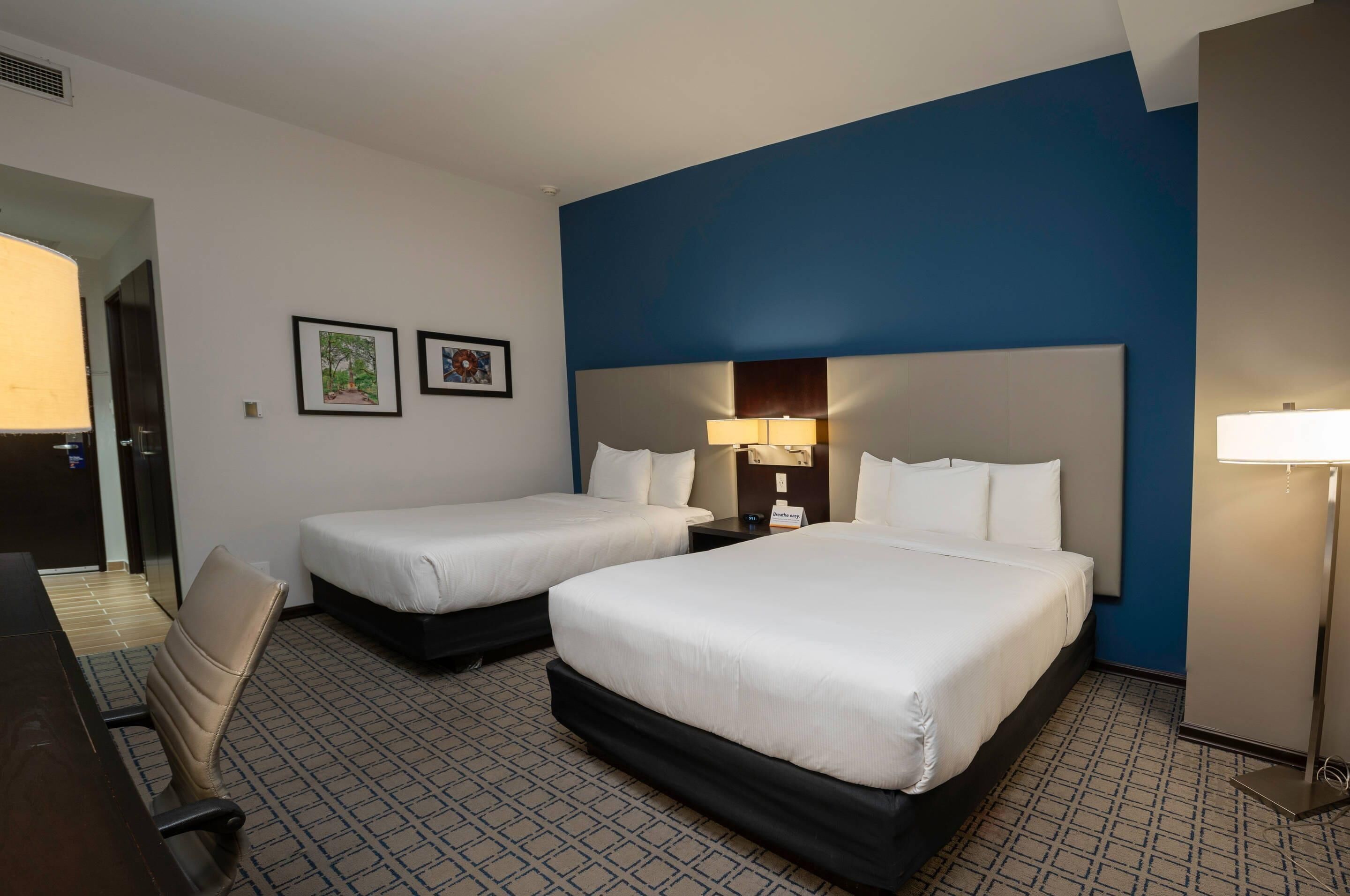 Een hotelkamer met twee bedden, een bureau en een stoel.