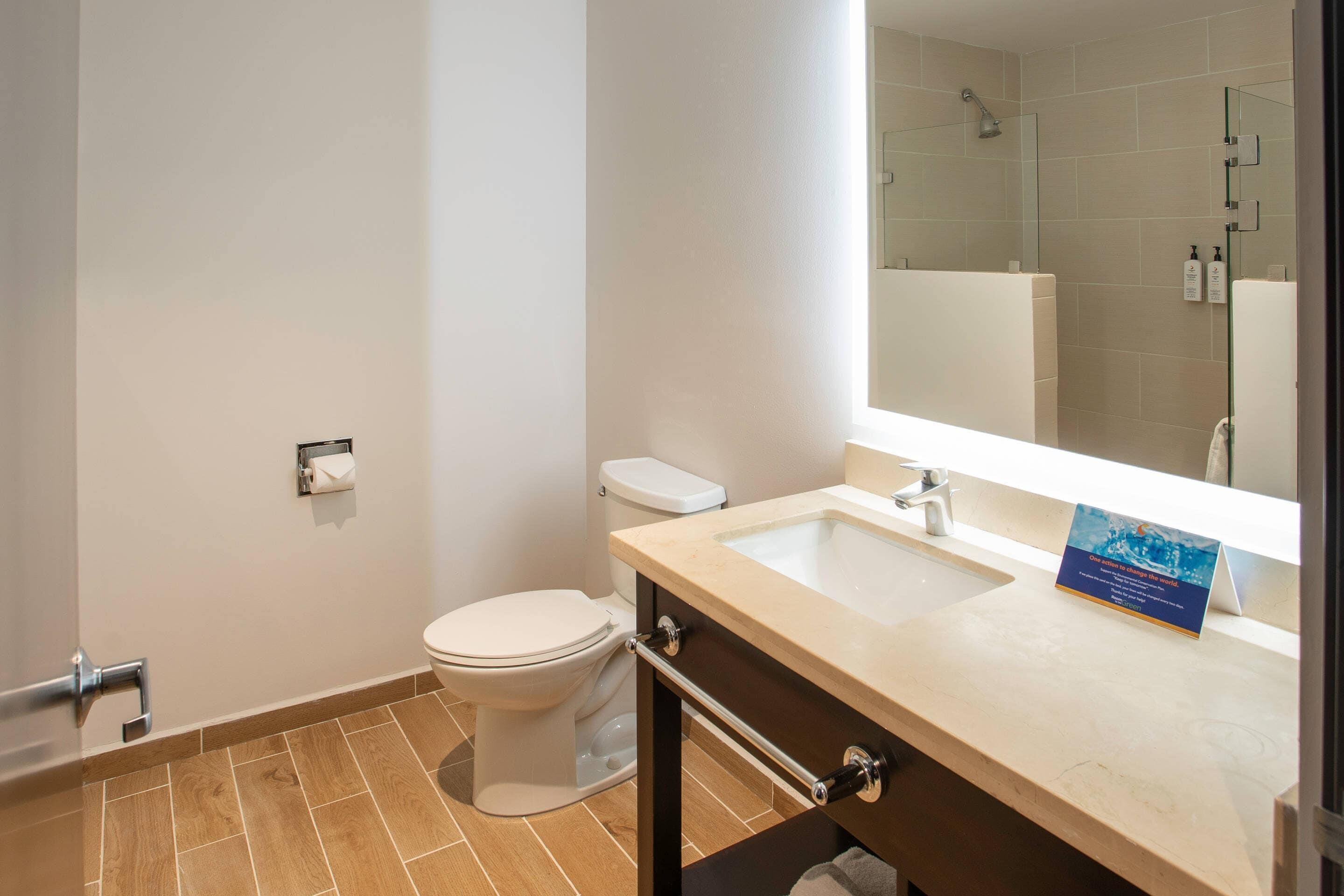 Un baño moderno con inodoro, lavabo y zona de ducha.