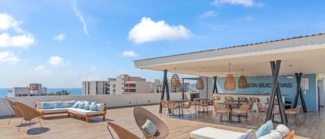 A rooftop terrace with outdoor seating, a covered area, and a view of the cityscape.