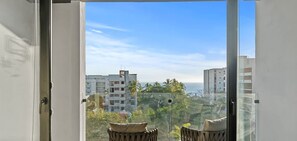 A view from a balcony with a clear sky, palm trees, and buildings in the background. - Vista Bucerias 402B - Rooftop Pool & Stunning Views (Bucerías)