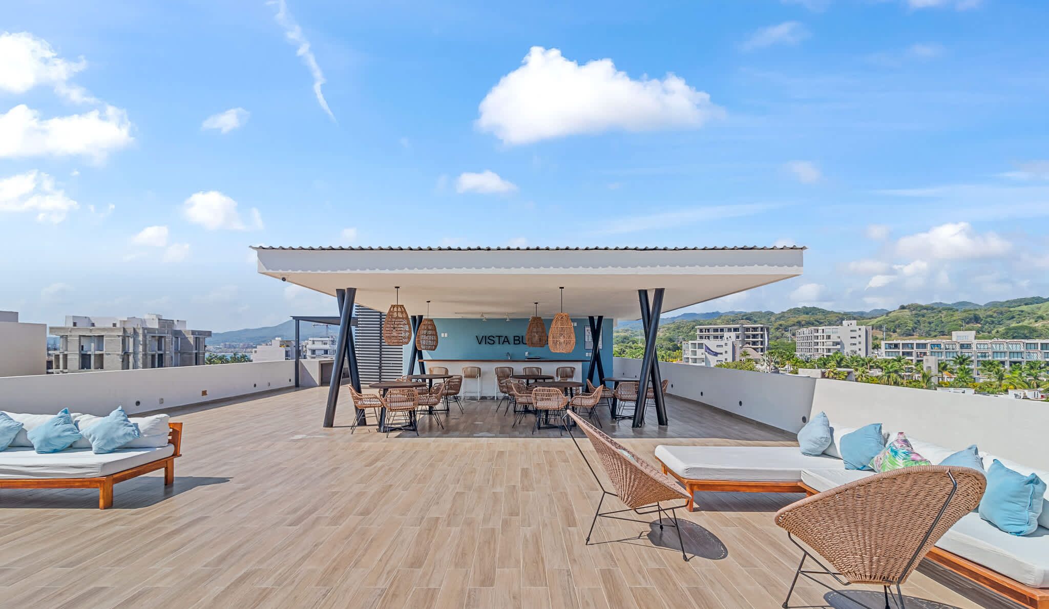 Terraço no telhado com área de estar coberta, espreguiçadeiras e um bar.
