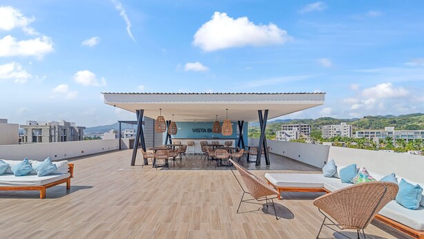 A rooftop terrace with a covered seating area, lounge chairs, and a bar. - Vista Bucerias 402B - Rooftop Pool & Stunning Views (Bucerías)