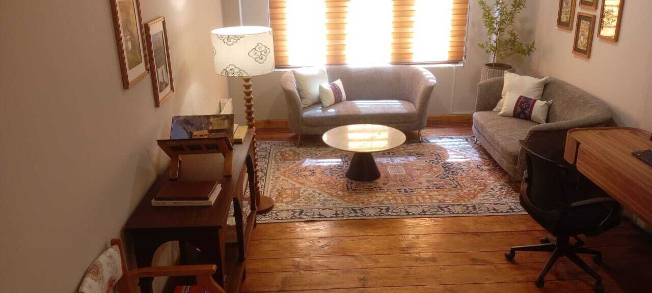 Ein Wohnzimmer mit einer Couch, einem runden Couchtisch, einer Lampe und einem Bücherregal.