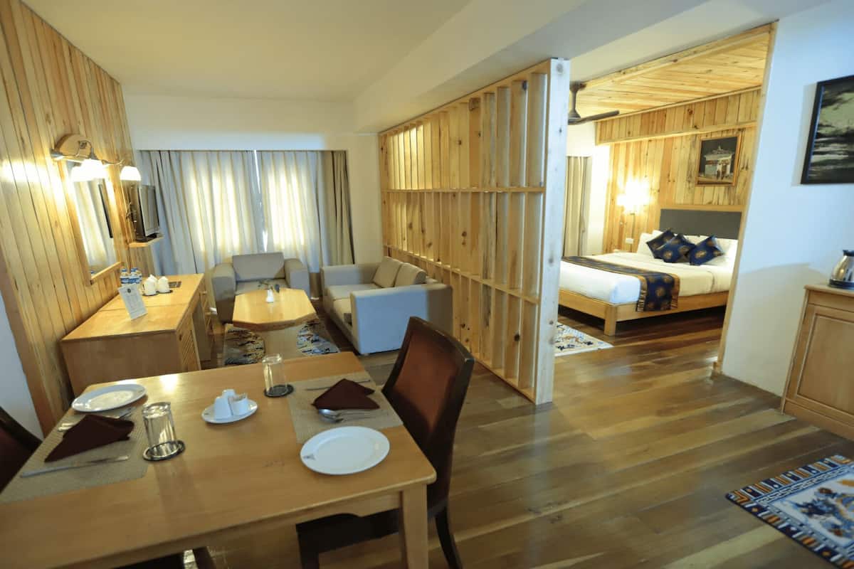 A hotel room with a dining area, a bed, and a kitchenette.