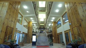 A hotel lobby with a central staircase, wooden paneling, and seating areas.