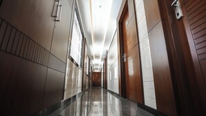 A long, polished hallway with wooden doors and a tiled floor. - Hotel Lakshmi Towers (Kangayam)