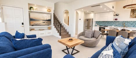 Un salon moderne avec des canapés bleus, une table basse en bois et un fauteuil gris.