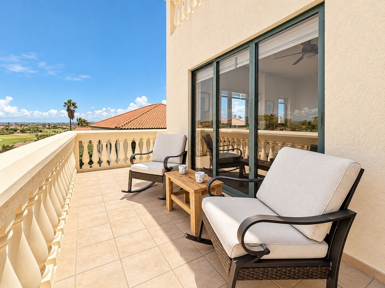 A balcony with a seating area, including a sofa and chairs, a small table, and a coffee cup.