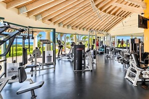 A gym with various exercise equipment, a wooden ceiling, and a view of the outdoors.