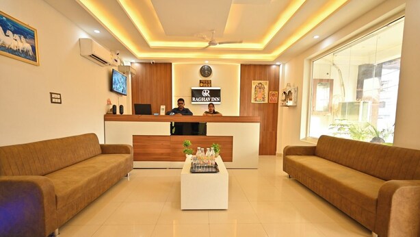 A hotel reception area with a reception desk, two sofas, a coffee table, and a large window. - Hotel Raghav Inn  (Faizabad)
