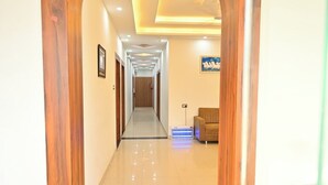 A hallway with a wooden archway leading to a room with a sofa and a television. - Hotel Raghav Inn  (Faizabad)
