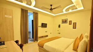 A hotel room with a bed, a desk, a TV, and a ceiling fan. - Hotel Raghav Inn  (Faizabad)