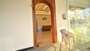 An office space with a wooden archway leading to a room with a couch and a sign that reads "Ravindra". - Hotel Raghav Inn  (Faizabad)