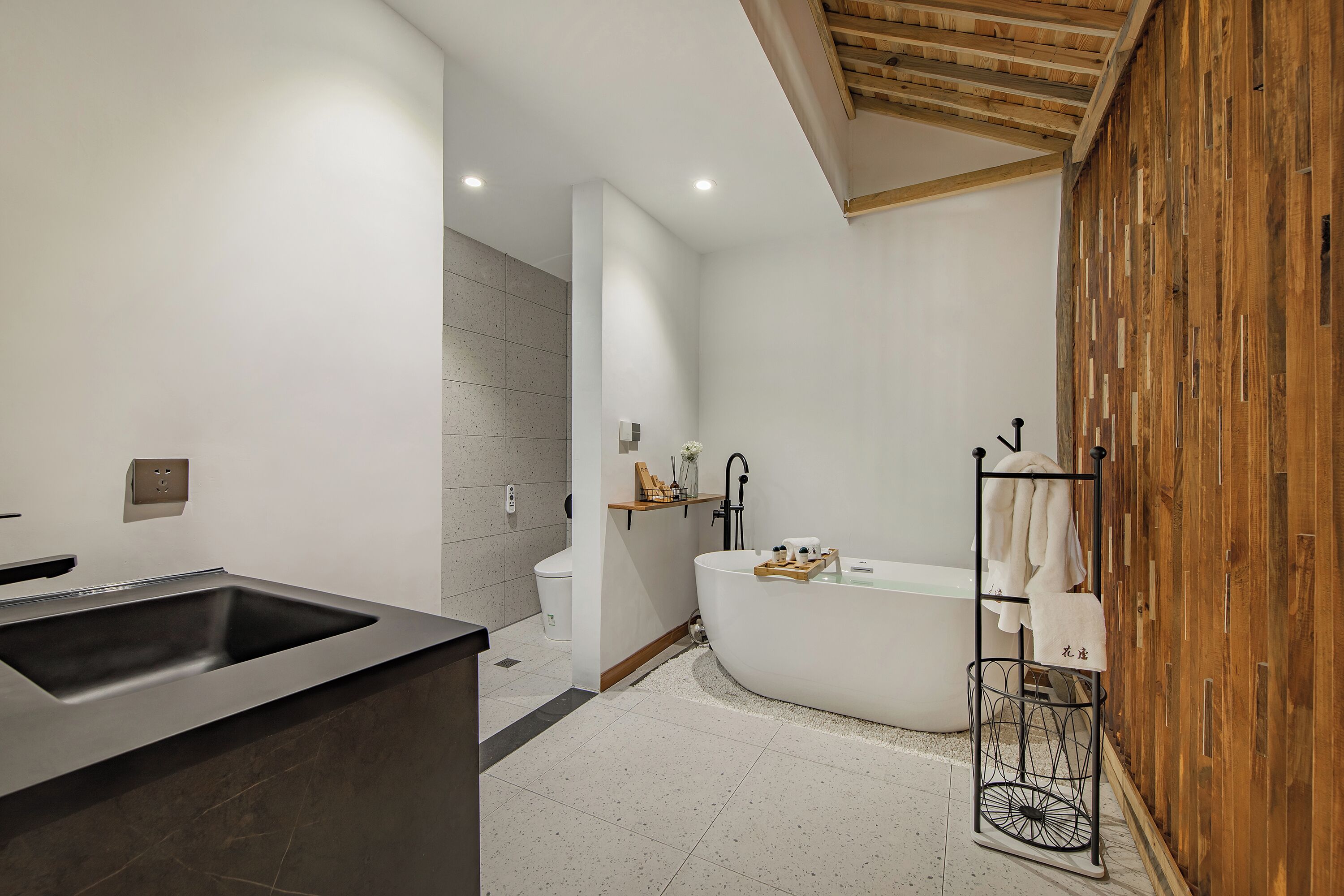 Ein modernes Badezimmer mit einer freistehenden Badewanne, einem großen Waschbecken und einer Holzvertäfelung.
