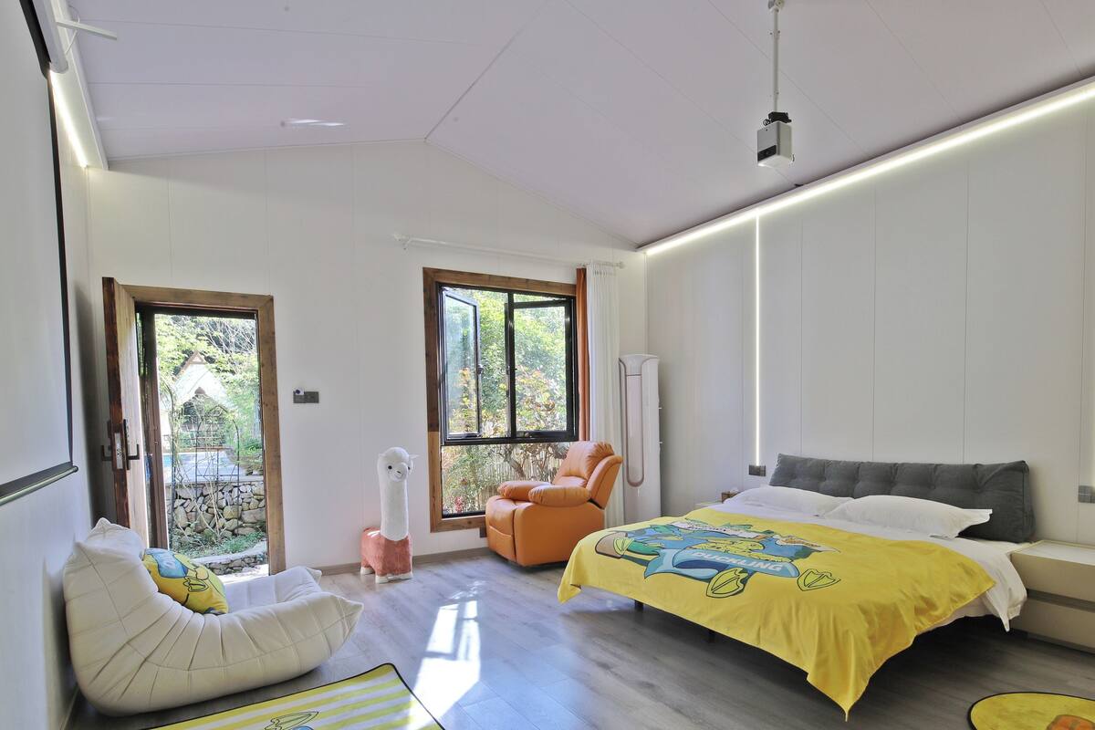 A modern bedroom with a bed, a chair, and a view of the outdoors.